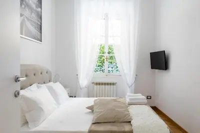 a white bedroom with a bed and a window at A World Aparts - 32 Calabria in Rome