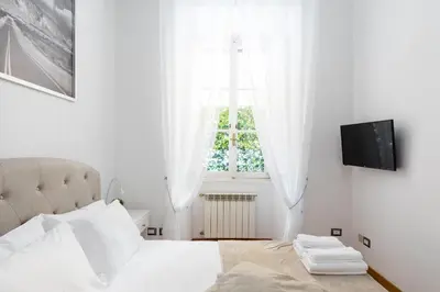 a white bedroom with a bed and a window at A World Aparts - 32 Calabria in Rome