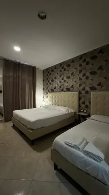 a bedroom with two beds and a wall with rocks at San Paolo Guest House in Rome