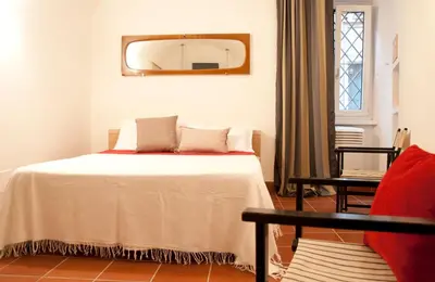 a bedroom with a bed with a mirror and a chair at TRASTEVERE - STUDIO APT. x 2 in Rome