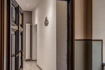 a hallway with a door with a clock on the wall at Vatican Royal Apartment in Rome