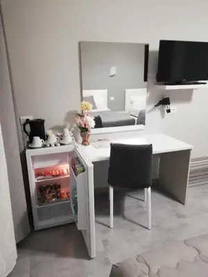 a white desk with a refrigerator and a chair in a room at Garden's Elide in Rome