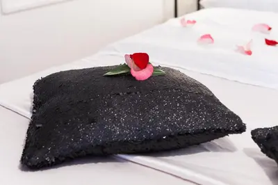 a black pillow with a rose on it on a bed at Ostiense Suites in Rome