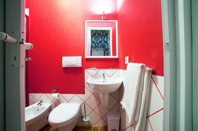 a red bathroom with a sink and a toilet at Ostiense Suites in Rome