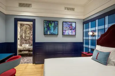 a bedroom with blue walls and a bed and a chair at The Independent Hotel in Rome