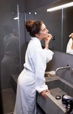 a woman standing in front of a bathroom mirror at Elysium Suites collection in Rome