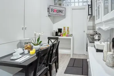 a white kitchen with a black table and chairs at Rhome Guest House in Rome