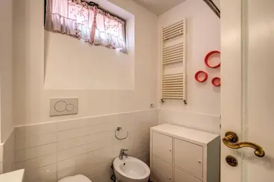 a white bathroom with a toilet and a window at Campo di Fiori 2 bedroom Via Giulia in Rome
