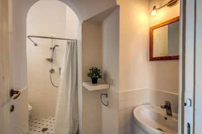 a white bathroom with a shower and a sink at Campo di Fiori 2 bedroom Via Giulia in Rome