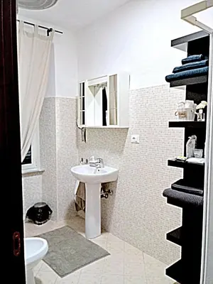 a white bathroom with a sink and a mirror at Appiolatino - Il Fenicottero in Rome