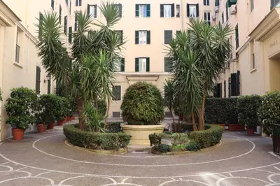 a courtyard with palm trees in front of a building at The Center Of Rome B&B in Rome