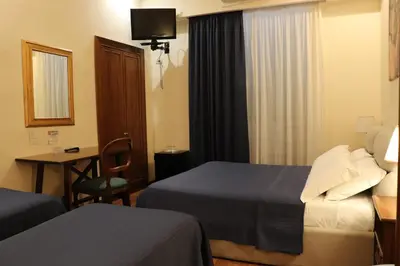 a hotel room with two beds and a table and a chair at The Center Of Rome B&B in Rome