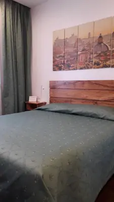 a bedroom with a bed with two paintings on the wall at L'Oasi al Pigneto - Guest house in Rome