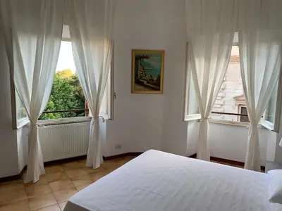 a bedroom with a bed and two large windows at Arion Holiday Home in Rome