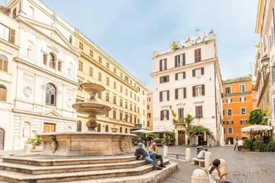 a group of people sitting around a fountain in a city at ColosseoDreamApartment in Rome