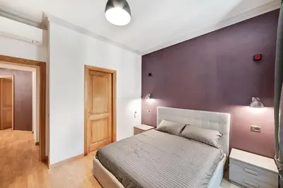 a bedroom with a bed and a purple wall at Peroni 8 Pax Brand New Apartment in Rome