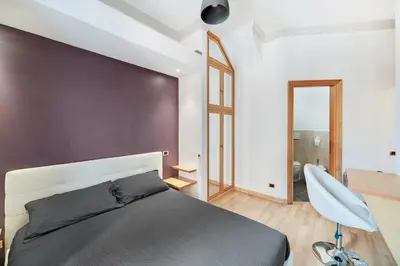 a bedroom with a bed and a purple wall at Peroni 8 Pax Brand New Apartment in Rome
