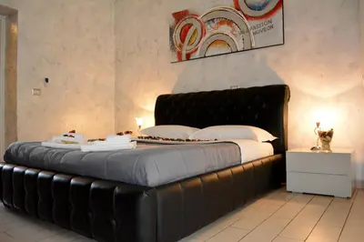 a large bed with a black leather headboard in a room at VaticanSky rooms in Rome