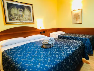 a hotel room with two beds and a basket of towels at Saint Peter Inn in Rome