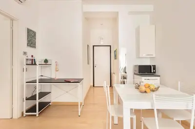 a white kitchen with a white table and chairs at World Wide Bed San Giovanni in Rome