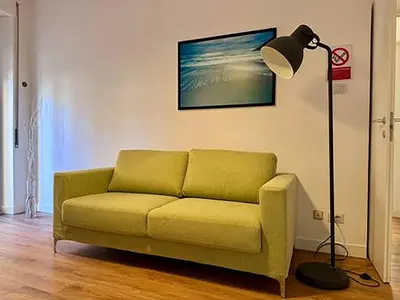 a living room with a green couch and a lamp at JHHIT Tuscolana Suite 03 with Terrace in Rome