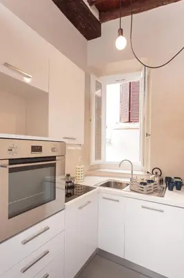 a kitchen with white cabinets and a sink and a window at Margana Tower in Rome