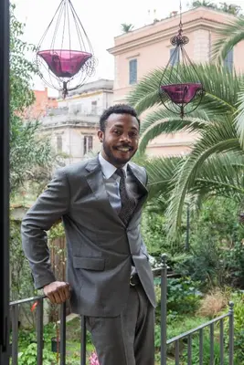 a man in a suit and tie standing next to a fence at Palm Gallery Hotel in Rome