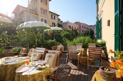 a patio with tables and chairs on a balcony at Palm Gallery Hotel in Rome