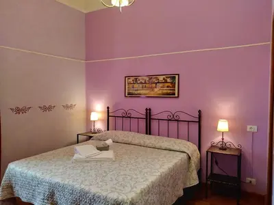 a bedroom with a bed with purple walls and two lamps at Rossi Hotel in Rome