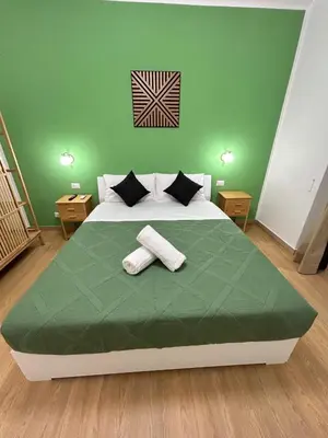 a green bedroom with a bed with two towels on it at San Peter Lory's Aparts in Rome