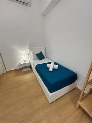a white bedroom with a bed with a blue blanket at San Peter Lory's Aparts in Rome