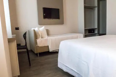 a hotel room with a bed and a chair and a tv at Hotel San Giovanni Roma in Rome