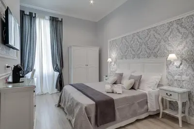 a white bedroom with a bed and a tv on the wall at Charme & Chic Luxury in Rome