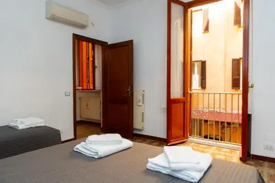 a room with two beds and a balcony with a door at Domus Candia in Rome