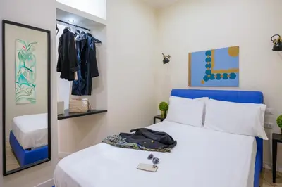 a bedroom with a blue bed and a mirror at Pantheon Unique Rooms in Rome
