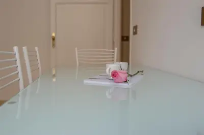 a pink rose sitting on a white table with a cup at Marbel - Casa vacanze in Rome