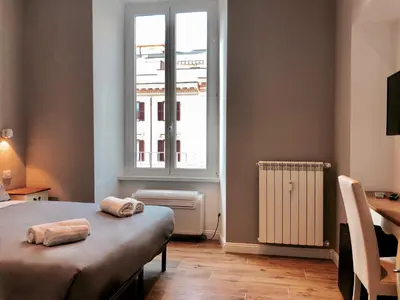 a bedroom with a bed and a window and a desk at Audrey's Roman Holidays - Rome Suites & Rooms in Rome