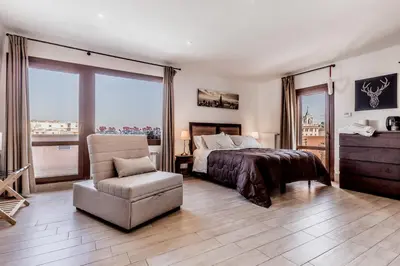 a bedroom with a bed and a chair and windows at My San Pietro Home, Vaticano in Rome