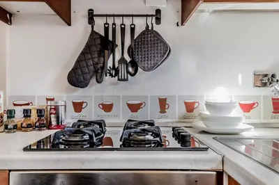 a kitchen with a stove with utensils on the wall at My San Pietro Home, Vaticano in Rome