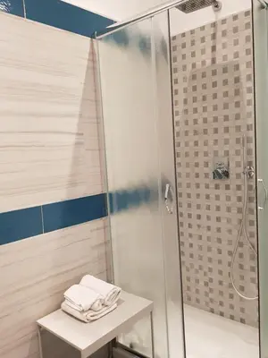 a bathroom with a shower with towels on a table at In Rome Trastevere Rooms in Rome