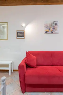 a red couch in a living room with a lamp at Rione Di Roma Center Apartment in Rome