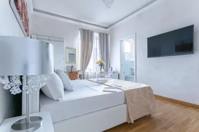 a white bedroom with a bed and a tv at Luxury Rome Guest House in Rome