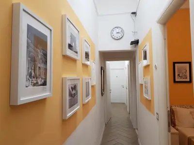 a hallway with pictures on the walls and a clock at My Trevi Rooms 88 in Rome
