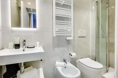 a white bathroom with a sink and a toilet at V Collection Relais Badoer in Rome