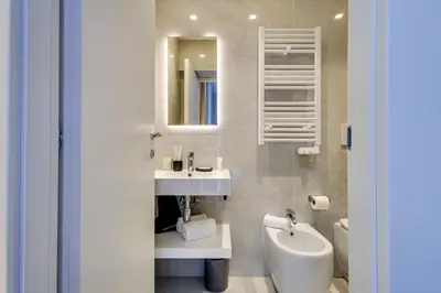 a bathroom with a sink and a toilet and a mirror at V Collection Relais Badoer in Rome
