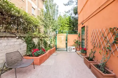 a courtyard with a gate and a chair and plants at Rome Apartment San Pietro - Monte del Gallo in Rome