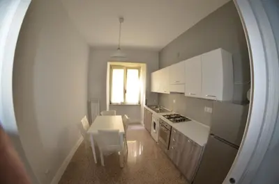 a kitchen with white cabinets and a table and chairs at Bed&bookofrome in Rome