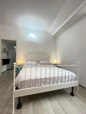 a white bed in a room with two lamps on tables at Delizioso Appartamento in Via di Monte Verde in Rome