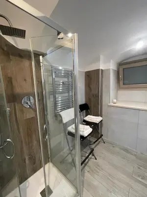 a bathroom with a shower and a chair in it at Delizioso Appartamento in Via di Monte Verde in Rome