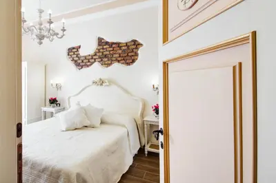 a bedroom with a white bed and a chandelier at Lunaria Suites Rome Vaticano in Rome